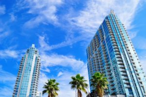 tall condo buildings, palm trees, blue sky, white clouds, windows